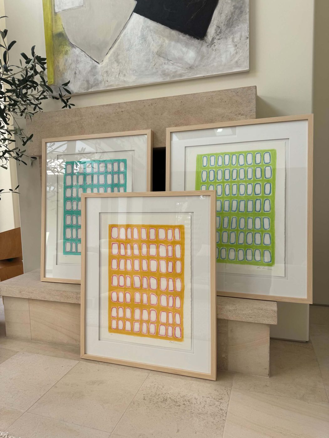 Several framed Lori Brunner works on paper leaning against a stone ledge