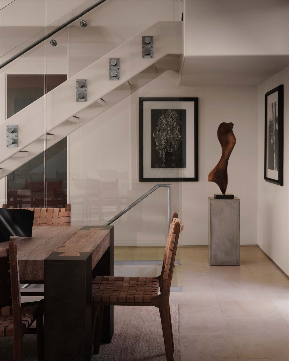 Entry beneath a glass staircase with a black-and-white painting and a carved wood sculpture