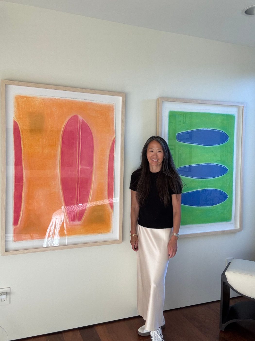 Lori Brunner standing between two of her framed surfboard prints